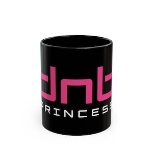 Puede incluir: Taza de cerámica negra con un logotipo "dnt" rosa y la palabra "princess" en blanco debajo.