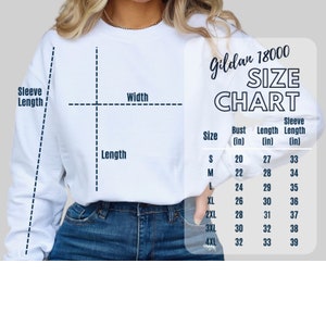 Może przedstawiać: Biała bluza z grafiką tabeli rozmiar&oacute;w. Tabela, oznaczona jako "Gildan 18000 SIZE CHART", zawiera wymiary biustu, długości i długości rękawa w calach dla rozmiar&oacute;w od S do 4XL. Bluza jest pokazana na osobie noszącej niebieskie dżinsy.