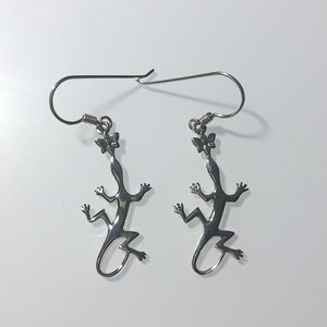 May include: Silver lizard earrings with a butterfly detail on the head.