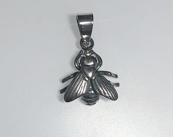 Puede incluir: Un colgante de abeja plateada con alas y cuerpo detallados. El colgante tiene un lazo en la parte superior para una cadena. Las alas de la abeja están extendidas y el cuerpo tiene detalles a rayas. El colgante es probablemente de metal.