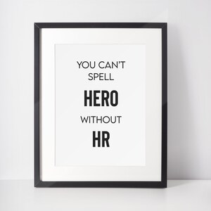 May include: Black framed print with the text "You can't spell hero without hr" in white.