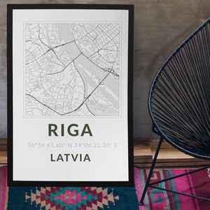 Op de afbeelding: Een zwart ingelijste poster met een kaart van Riga, Letland. De poster heeft de naam van de stad en de coördinaten in groene tekst.