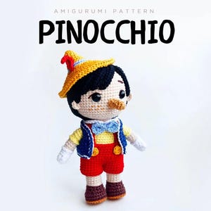 Peut inclure: Poupée Pinocchio au crochet, avec un chapeau jaune, un gilet bleu, un short rouge et des chaussures marron. La poupée a un long nez et un nœud papillon bleu. Le texte "PINOCCHIO" est au-dessus.
