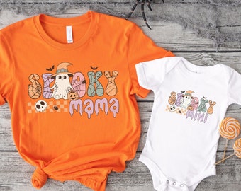 May include: Orange and white t-shirts with a spooky Halloween design. The adult shirt says "Spooky Mama" and the baby shirt says "Spooky Mini".