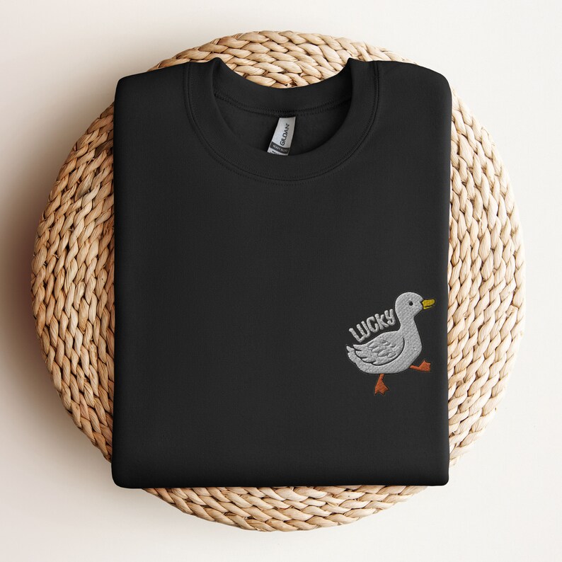 May include: Black sweatshirt with a white embroidered duck and the word "LUCKY" on the left side of the chest.