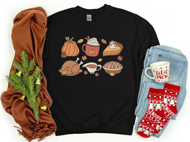May include: Black sweatshirt with a Thanksgiving-themed design featuring a pumpkin, turkey, pie, gravy, and a cup of hot chocolate.