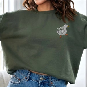 May include: A green sweatshirt with a white embroidered duck and the word "LUCKY" on the front.