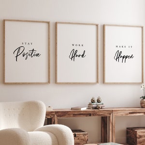 May include: Three framed motivational posters with white backgrounds and black text. The posters are hung on a white wall. The text on the posters reads "Stay Positive", "Work Hard", and "Make It Happen".