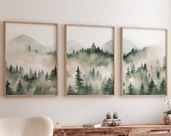 May include: Three framed watercolor paintings of a misty forest scene with green trees and mountains. The paintings are hanging on a white wall above a wooden table with a white armchair and a round wooden coffee table.