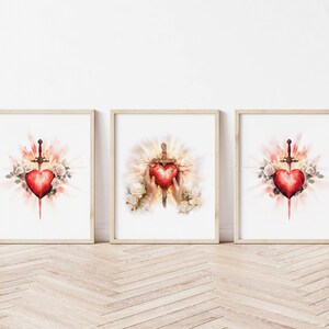 Pode incluir: Tr&ecirc;s impress&otilde;es emolduradas com ilustra&ccedil;&otilde;es em aquarela de um cora&ccedil;&atilde;o trespassado por uma espada, rodeado de rosas brancas e uma luz dourada. O cora&ccedil;&atilde;o &eacute; vermelho e a espada &eacute; prateada.