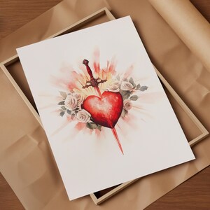 Pode incluir: Uma pintura em aquarela de um cora&ccedil;&atilde;o vermelho atravessado por uma espada, rodeado de rosas brancas e um brilho radiante.