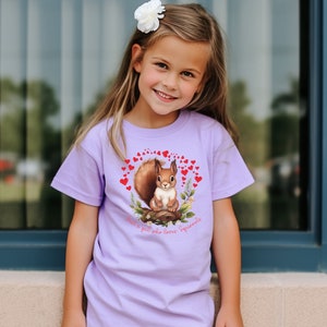 May include: A purple t-shirt with a graphic of a squirrel surrounded by red hearts. The text "Just a gal who loves Squirrels" is printed below the squirrel.