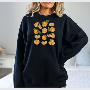 May include: Black sweatshirt with a graphic print of orange slices and leaves.