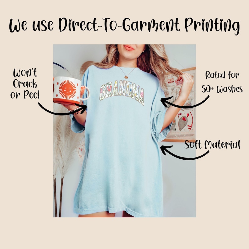 May include: A light blue t-shirt with the word "Grandma" printed in colorful letters. The shirt is made with a soft material and is rated for 50+ washes.