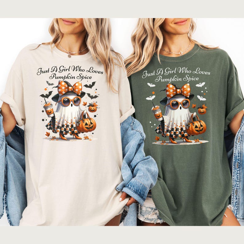 May include: Two t-shirts, one cream and one olive green, featuring a cartoon ghost character. The ghost wears sunglasses, a bow, and a checkered skirt, holding a pumpkin and a coffee. Text reads "Just A Girl Who Loves Pumpkin Spice."