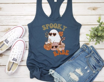May include: A teal blue tank top with a graphic of a ghost wearing heart-shaped sunglasses and pumpkins. The text "Spooky Babe" is printed on the shirt.