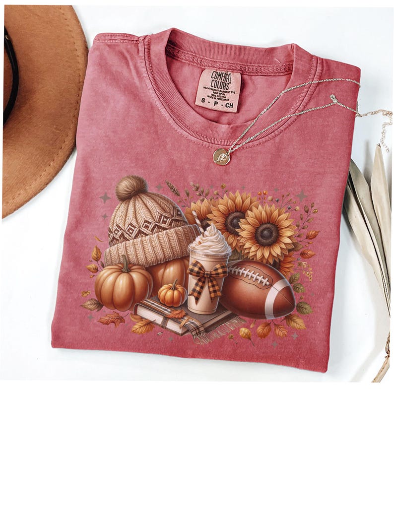 May include: A red t-shirt with a fall-themed design featuring a pumpkin, a coffee cup, a football, a knitted hat, and sunflowers. The text "COMFORT COLORS" is visible on the tag.