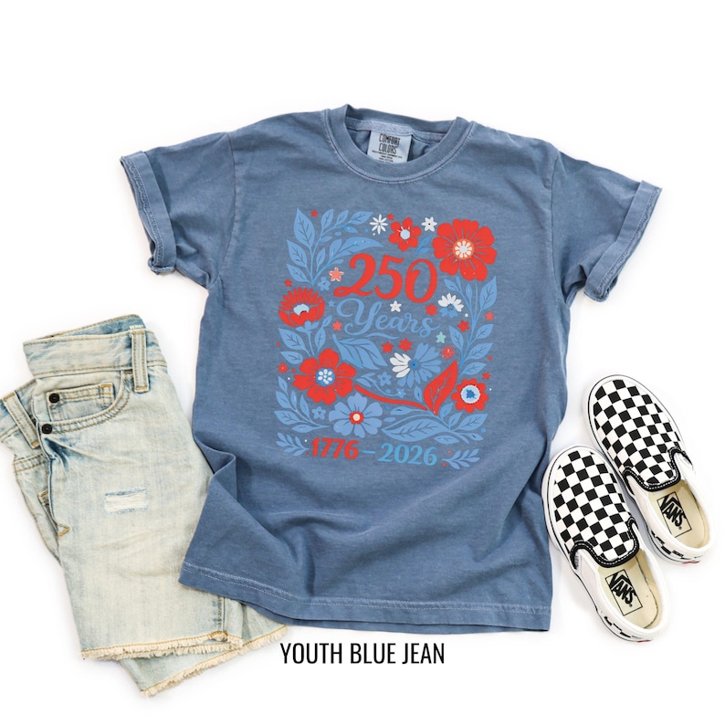 May include: A blue t-shirt with a floral design featuring the text "250 Years 1776-2026". The shirt is paired with denim shorts and black and white checkered slip-on shoes. The words "YOUTH BLUE JEAN" are printed at the bottom.