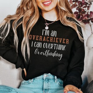 May include: A black sweatshirt with the text "I'm an overachiever I can overthink overthinking" in brown and white lettering.