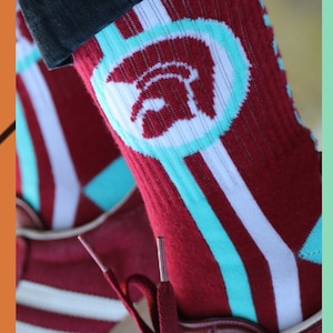 May include: Red and white striped socks with a turquoise stripe and a white circle with a red helmet graphic.