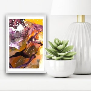 May include: Abstract painting in a white frame with a yellow, brown, purple, and white color scheme. The painting is on a white shelf with a white lamp and a succulent plant in a white pot.