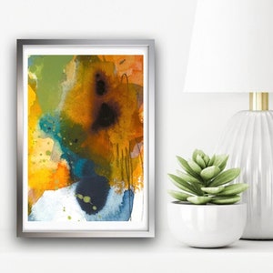 Puede incluir: Pintura abstracta de acuarela en un marco plateado. La pintura presenta una mezcla de colores amarillos, naranjas, verdes, azules y negros en un estilo fluido.