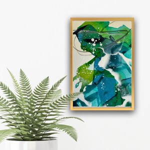 May include: Abstract painting with green, blue, and white paint splatters and swirls on a canvas. The painting is framed in a gold frame.