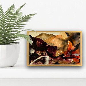 May include: Abstract painting in a gold frame with brown, orange, and white colors. The painting has a textured look and appears to depict a landscape.