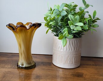 Pode incluir: Um vaso de vidro castanho com uma borda ondulada e um vaso de cerâmica branco e castanho com plantas verdes de folha.