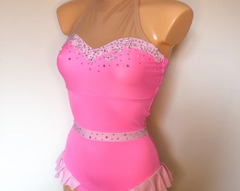 May include: A pink dance leotard with a sheer mesh halter neckline, embellished with rhinestones. The leotard has a ruffled skirt and a pink ribbon belt.
