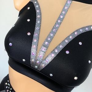 Puede incluir: Top de traje de baile negro con un panel de malla y ribete plateado. La parte superior est&aacute; decorada con diamantes de imitaci&oacute;n iridiscentes.