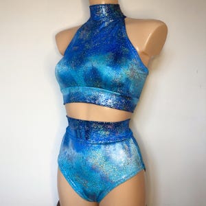 May include: A blue and silver halter top and high-waisted bottoms with a sparkly, iridescent finish. The set is made of a stretchy, comfortable fabric.