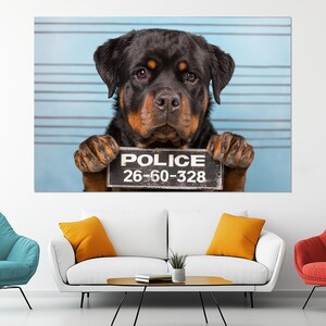 May include: A Rottweiler dog holds a sign that reads "POLICE 26-60-328" against a light blue background with horizontal lines. The dog has black and brown fur and is looking directly at the camera.