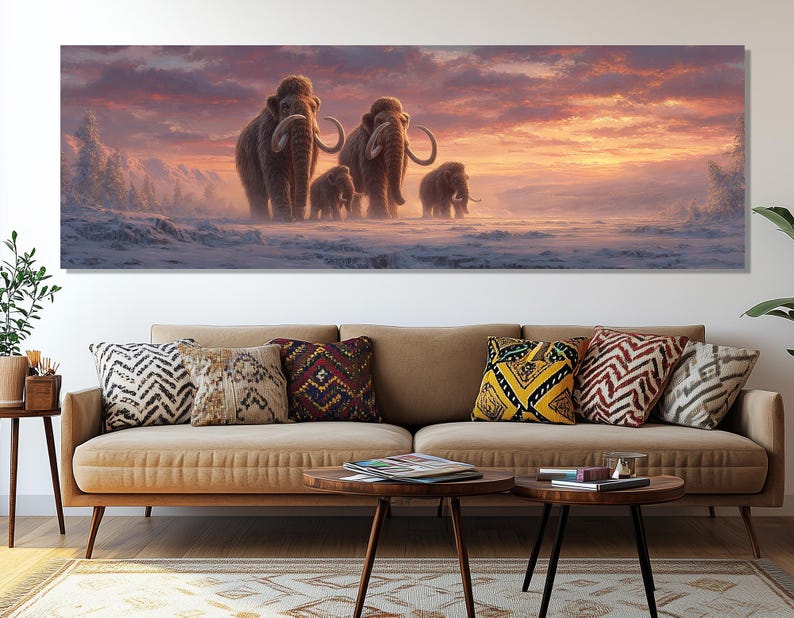 May include: A panoramic canvas print depicts a family of woolly mammoths walking across a snowy landscape. The artwork features a warm sunset with shades of orange and pink, creating a serene and prehistoric scene.
