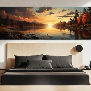 Op de afbeelding: Een panoramische canvas print die een serene meer scène bij zonsondergang toont. Het kunstwerk toont een levendige lucht met oranje en gele tinten, die reflecteren op het water. Bomen omzomen de oever van het meer, met een berg in de verte. De print wordt boven een bed weergegeven.