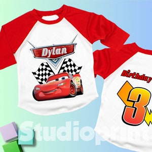 May include: Red and white baseball style t-shirt with a red race car and checkered flags. The shirt says "Dylan" on the front and "Birthday Boy 3" on the back.