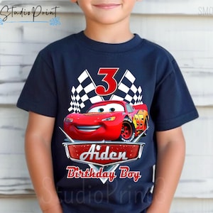 Puede incluir: Una camiseta azul marino con un gr&aacute;fico de un coche de carreras rojo, banderas a cuadros y el n&uacute;mero 3. El texto "Aiden Birthday Boy" est&aacute; impreso debajo del coche.
