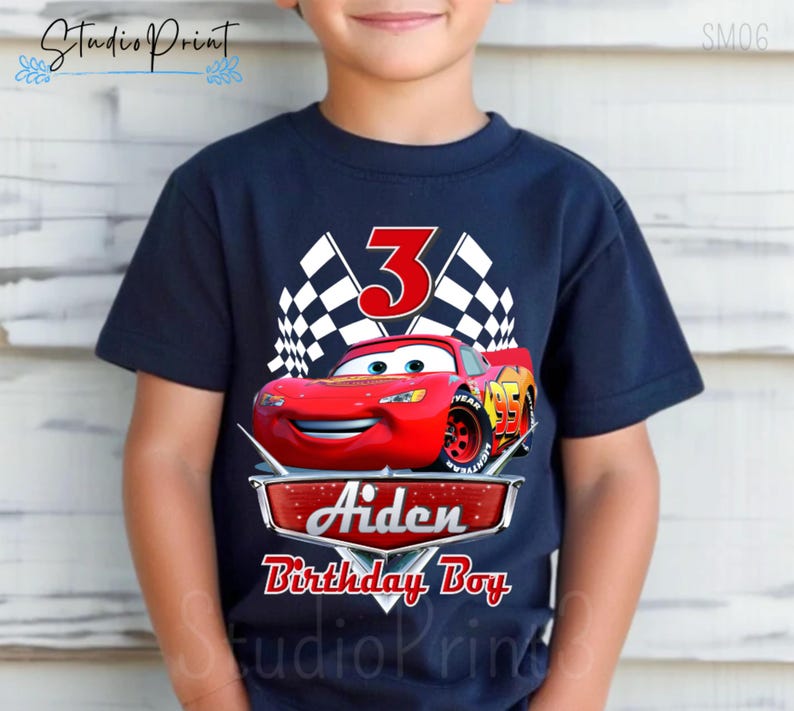 Puede incluir: Una camiseta azul marino con un gr&aacute;fico de un coche de carreras rojo, banderas a cuadros y el n&uacute;mero 3. El texto "Aiden Birthday Boy" est&aacute; impreso debajo del coche.
