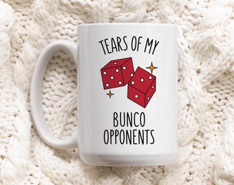 May include: White ceramic mug with a handle, featuring the text "TEARS OF MY BUNCO OPPONENTS" in black. The mug has a graphic of two red dice with white dots and gold star accents.