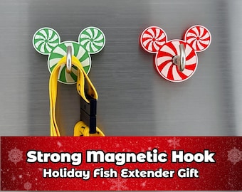 May include: Two magnetic hooks shaped like Mickey Mouse heads, one green and white, the other red and white, with silver hooks. A yellow lanyard hangs from the green hook. The text "Strong Magnetic Hook Holiday Fish Extender Gift" is at the bottom.