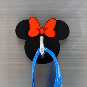 May include: Black and red Minnie Mouse-shaped hook with a silver hook. A blue ribbon is hanging from the hook.