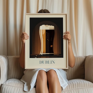 A person is sitting on a couch holding a framed picture of a beer mug with the word "DUBLIN" written on it.