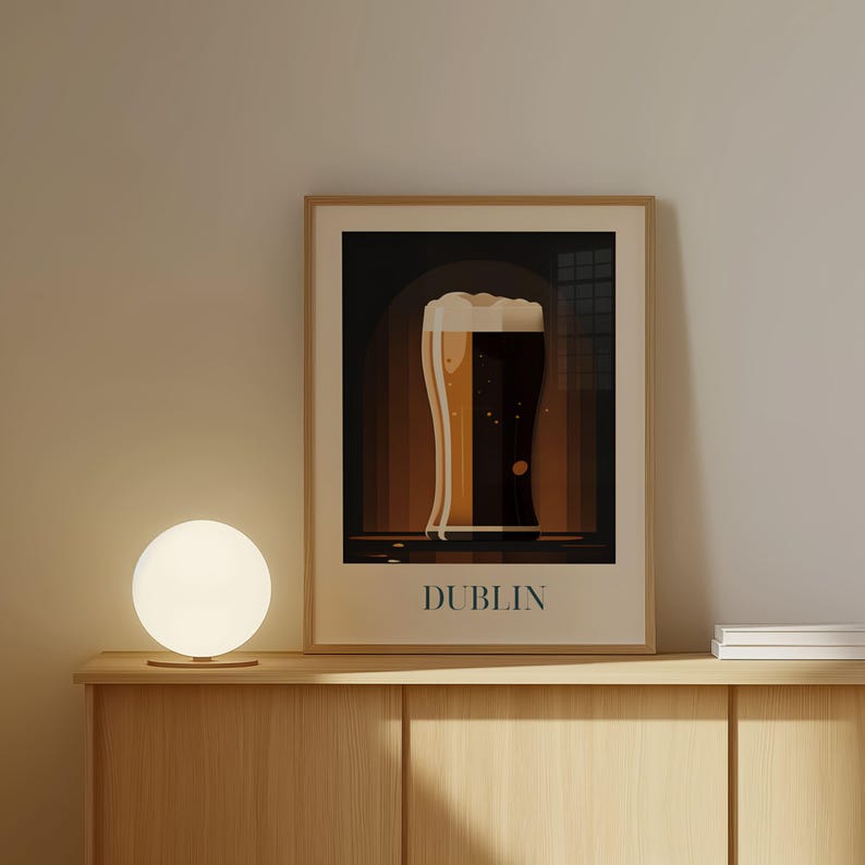 a framed poster of a glass of beer with the word "DUBLIN" written on it, placed on a wooden shelf or cabinet.