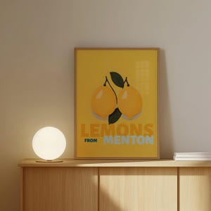 a framed poster with a yellow background and an illustration of two lemons. The poster is placed on a wooden shelf, and there is a round light fixture on the shelf.