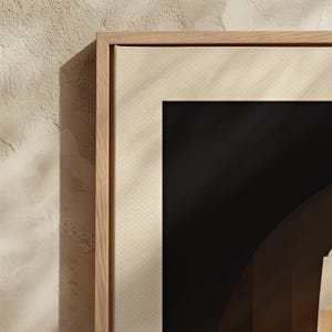 May include: A close-up of a wooden frame with a cream-colored mat. The frame is partially obscured by a shadow from the left. The mat has a subtle textured pattern.