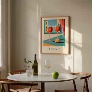a dining table with a green apple, a bottle of wine, and two wine glasses, set against a wall with a framed poster of a cityscape and a window.