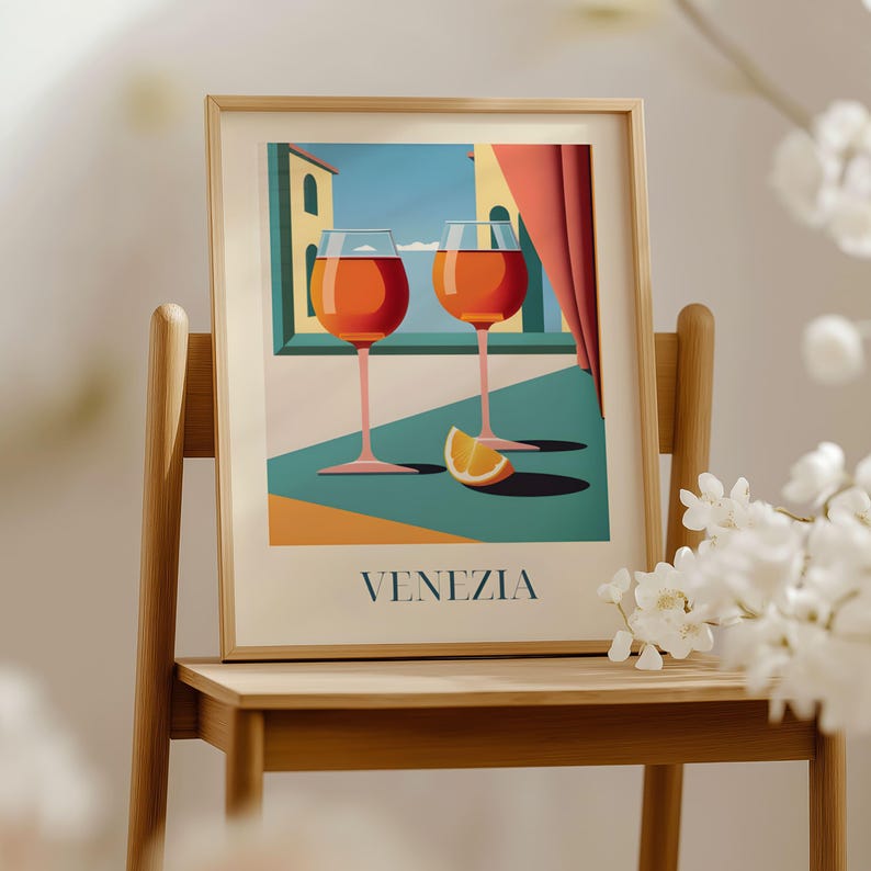 a framed illustration of two wine glasses with orange slices, set against a backdrop of a building and a window, with the word "VENEZIA" written below the illustration.