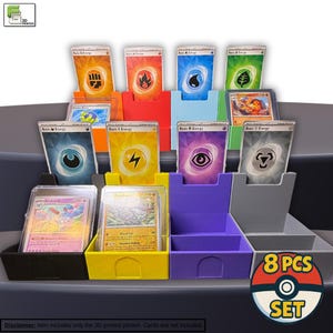 May include: A set of eight multi-colored 3D-printed card holders, each designed to hold trading cards. The holders are in various colors, including red, blue, yellow, and purple. The image also shows several trading cards with different energy symbols.