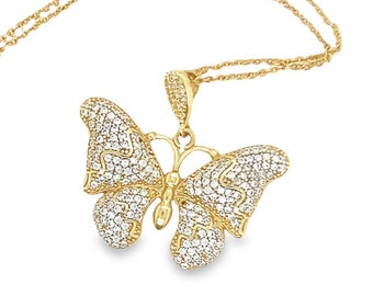 May include: A gold-colored butterfly pendant necklace. The butterfly pendant is encrusted with small, clear gemstones. The necklace chain is also gold-colored and delicate. The butterfly's wings are spread, and the design is detailed.