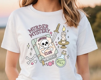 Peut inclure: T-shirt blanc avec un motif graphique d'un livre avec un crâne et des os croisés, une dague, une bougie et une fiole de potion. Le livre dit "Murder Club" et la fiole de potion dit "Kill". Le texte au-dessus du livre dit "Murder Mystery".